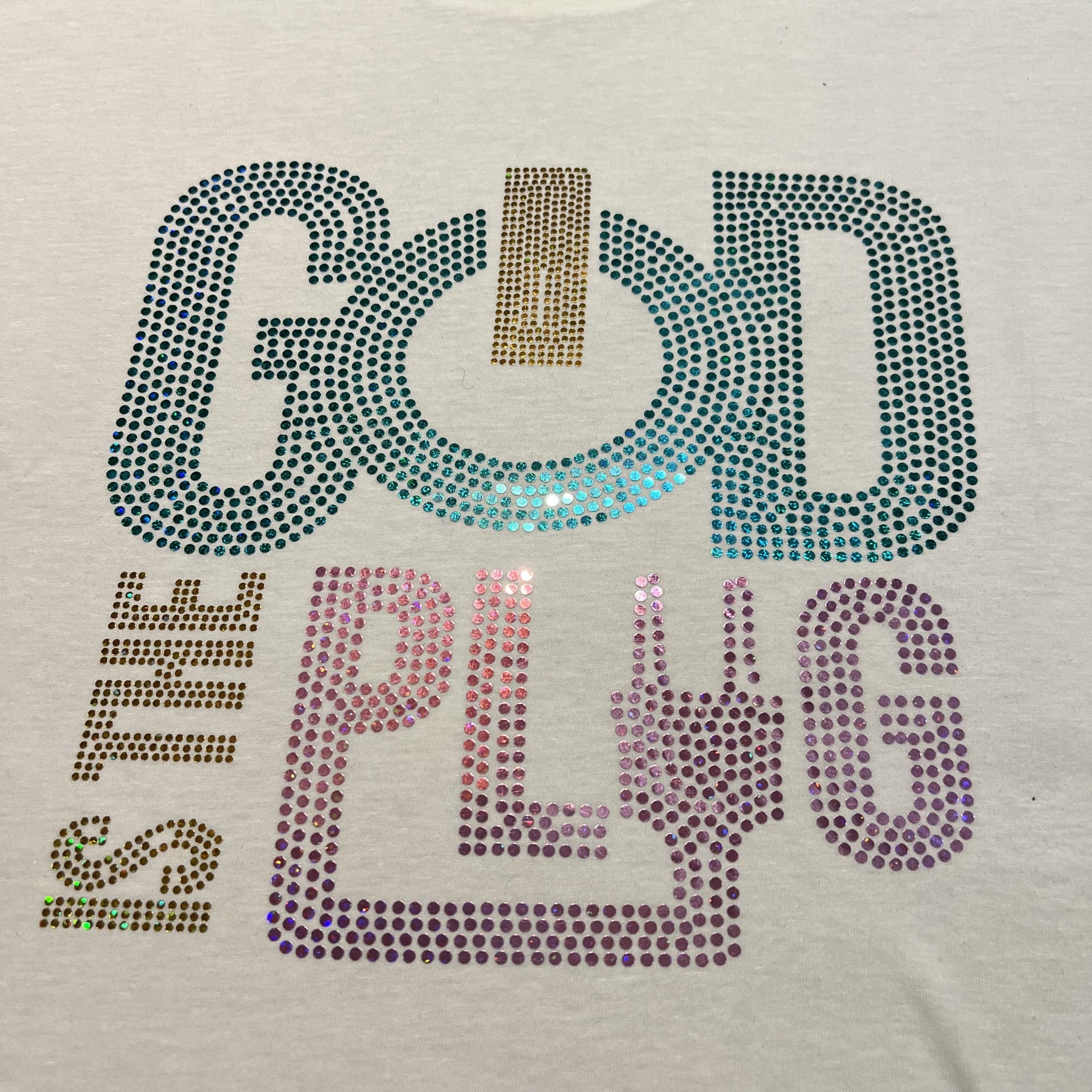 graphic design that reads GOD IS THE PLUG in multicolor sparkle lettering